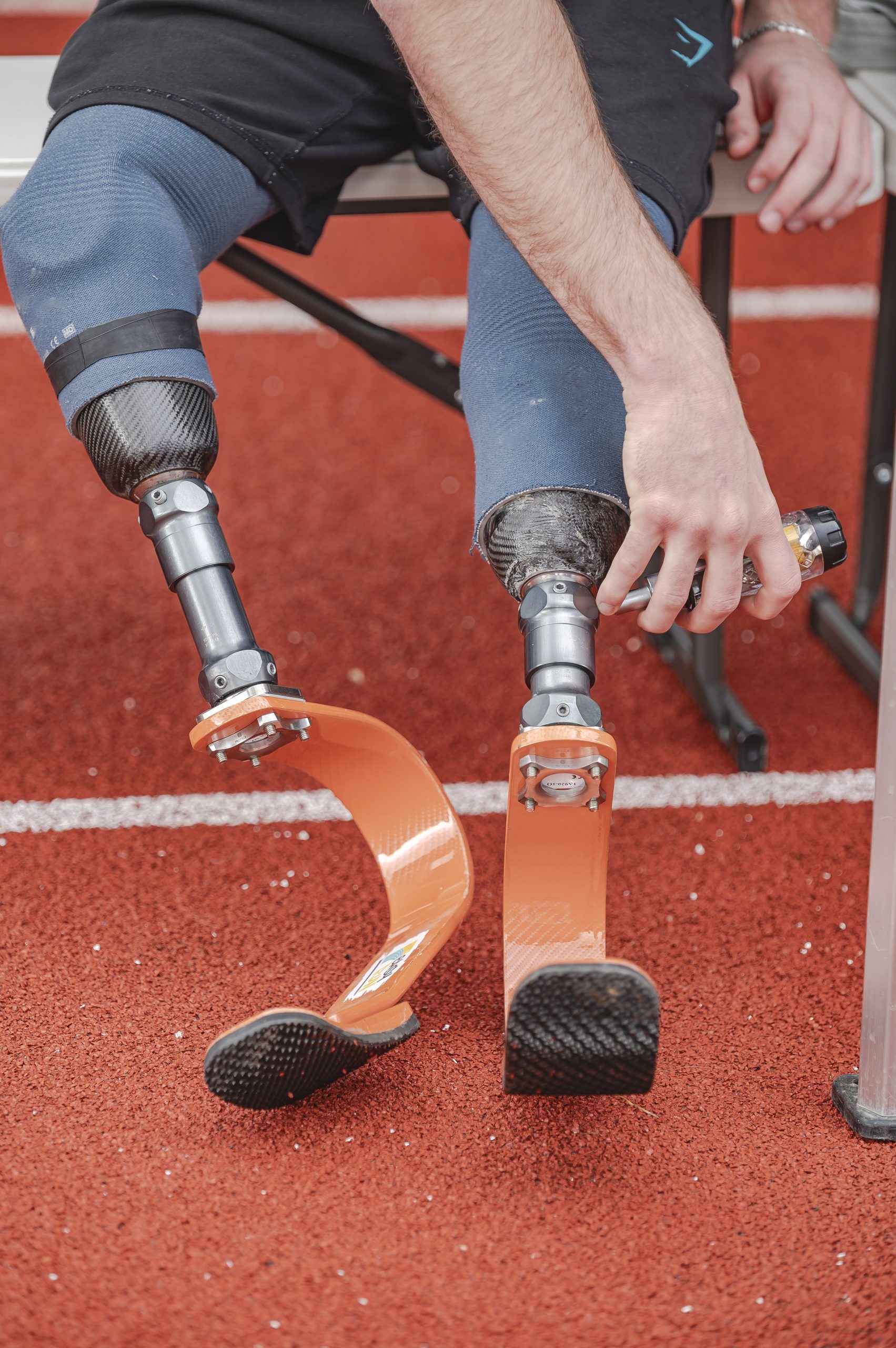 ACTIONS-Sport-2025 une photo d'une personne double amputée en train d'adapter des lames de course pour pouvoir courir