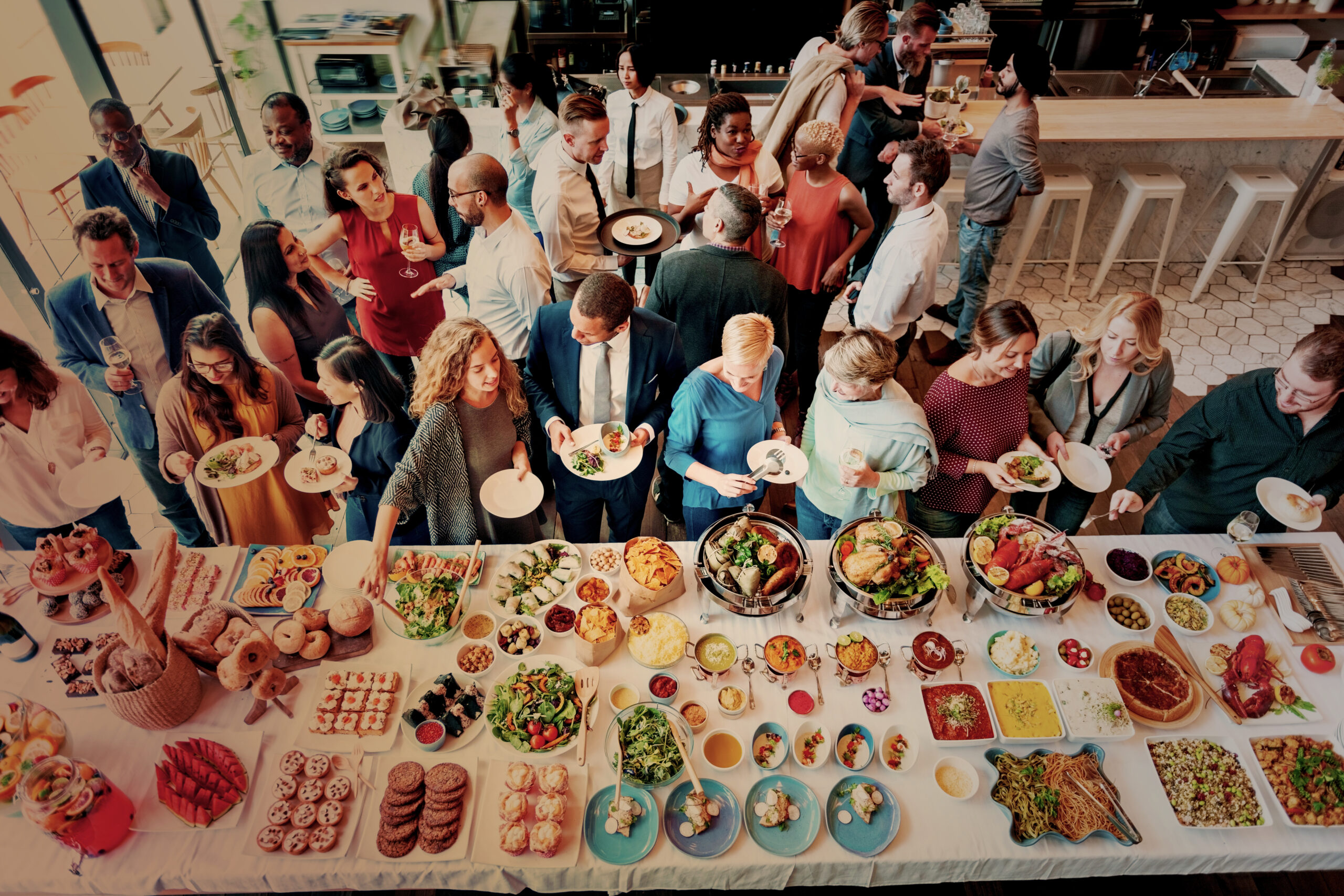 photo d'un cocktail convivial avec buffet coloré et des personnes en train de manger et de discuter.