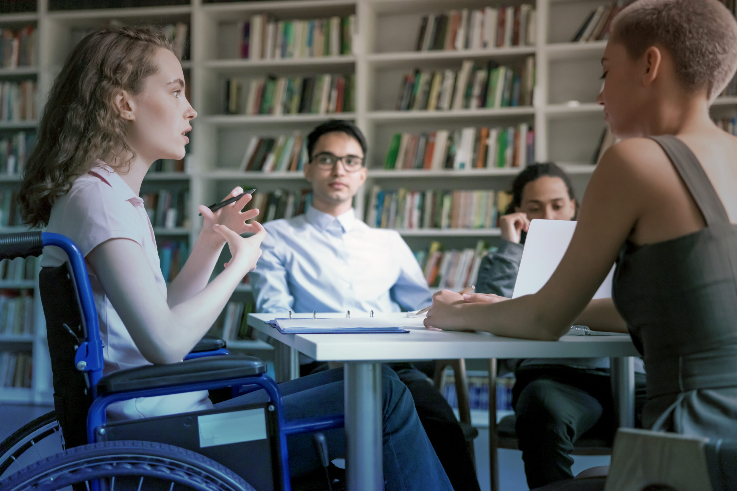 ACTIONS-InsertionPro-2025 jeunes dans une bibliothèque en train de travailler avec une jeune fille en fauteuil